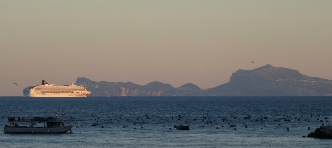 A cruise ship heads out of the Bay of Naples past the island of Capri.