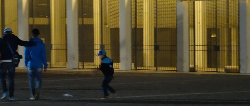 Match over - a young boy kicks a plastic bottle home