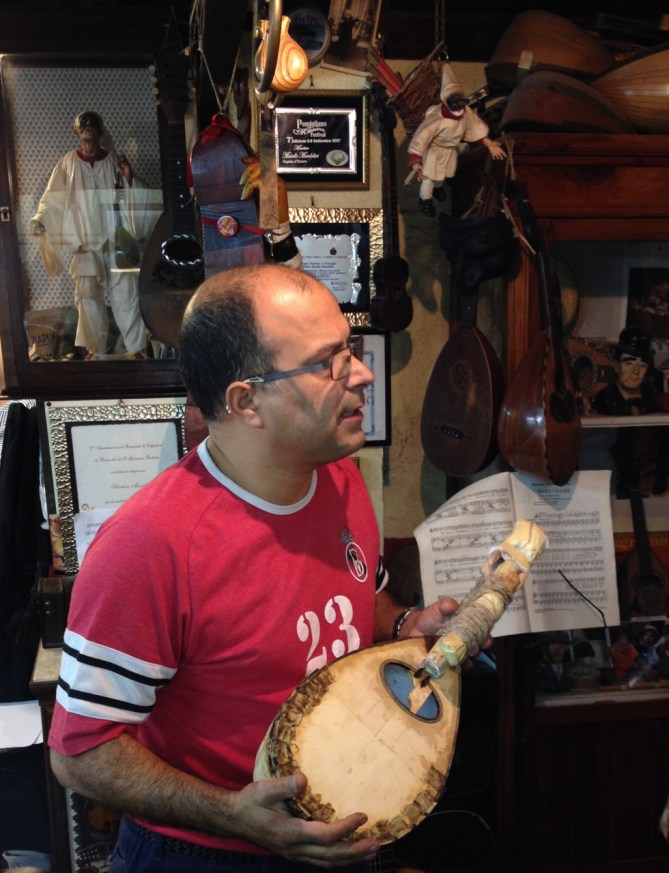 Luthier Salvatore Masiello explaining the making of the mandolin to the crowd in his tiny 'bottega' in Naples, Italy