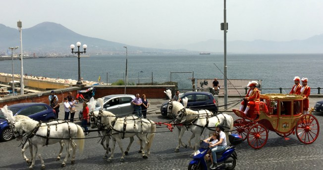 The carriages make their way along the seafront of Naples, Italy