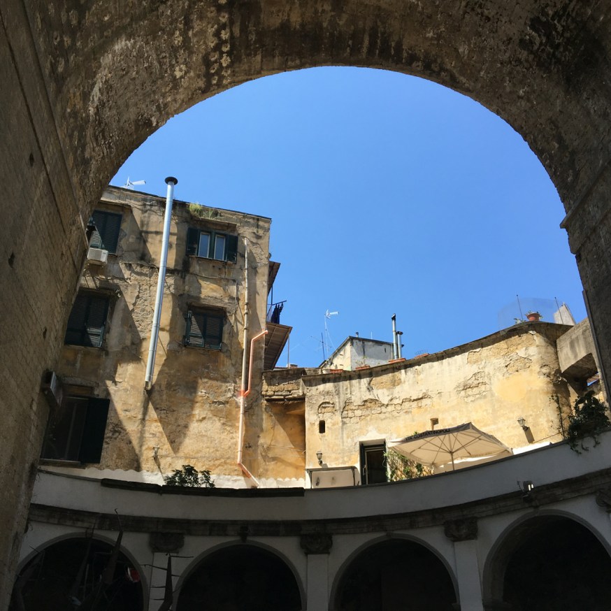 The leg of the bridge that stomps through the middle of the curved cloisters of the Basilica di Santa Maria della Sanità in Naples, Italy